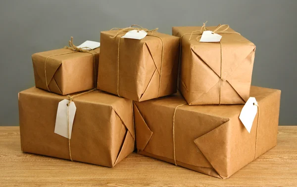 Parcels boxes with kraft paper, on wooden table on grey background — Stock Photo, Image