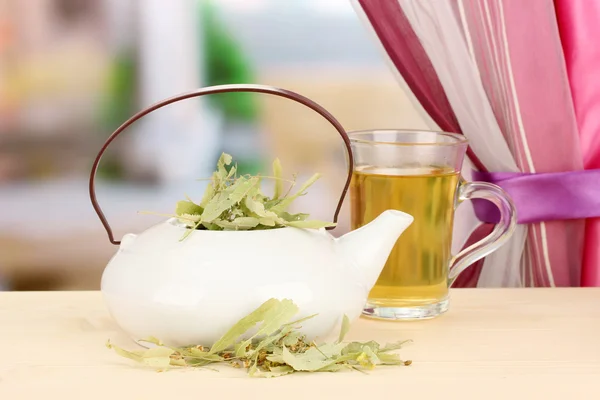 Dried herbs in teapot on wooden table, on bright background. Conceptual photo of herbal tea. — Stock Photo, Image