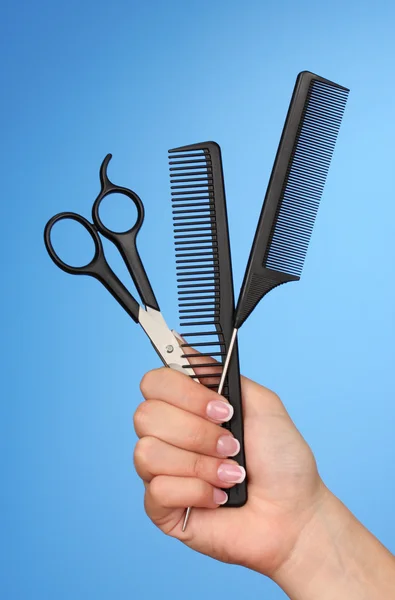 Color combs and scissors in female hand on color background — Stock Photo, Image