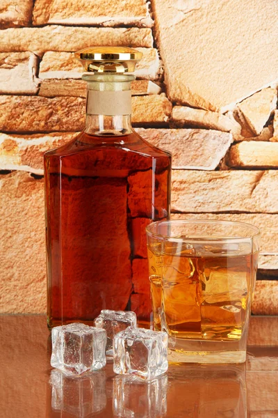 Bouteille et verre de whisky et de glace sur fond de mur de briques — Photo