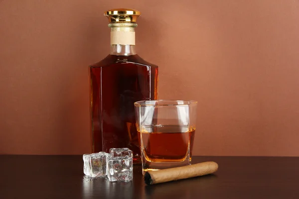 Bottiglia e bicchiere di whisky e ghiaccio su sfondo marrone — Foto Stock