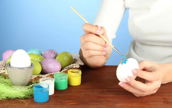 Young woman painting Easter eggs, on color background — Stock Photo, Image