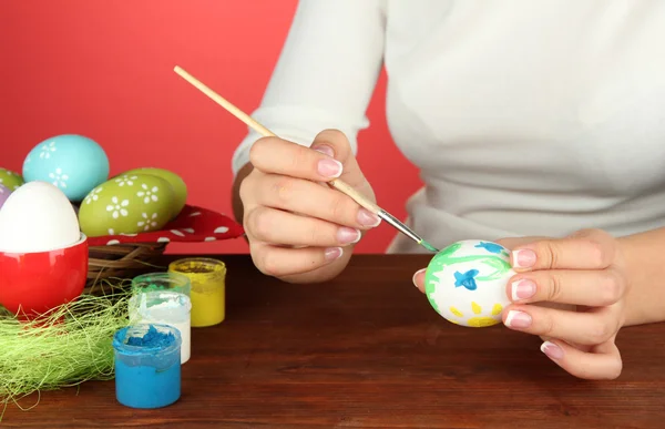 Mujer joven pintando huevos de Pascua, sobre fondo de color —  Fotos de Stock