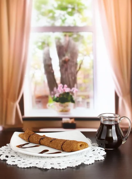 Crêpes sucrées sur assiette avec lait condensé sur table dans la pièce — Photo