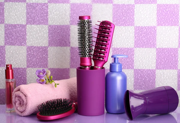 Hair brushes, hairdryer and cosmetic bottles in bathroom — Stock Photo, Image