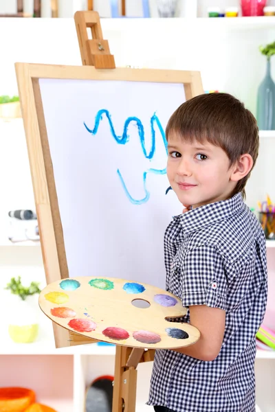 Little boy painting paints picture on easel — Stock Photo, Image