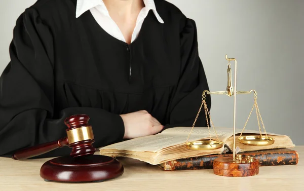 Суддя сидить за столом під час судових засідань на сірому фоні — стокове фото