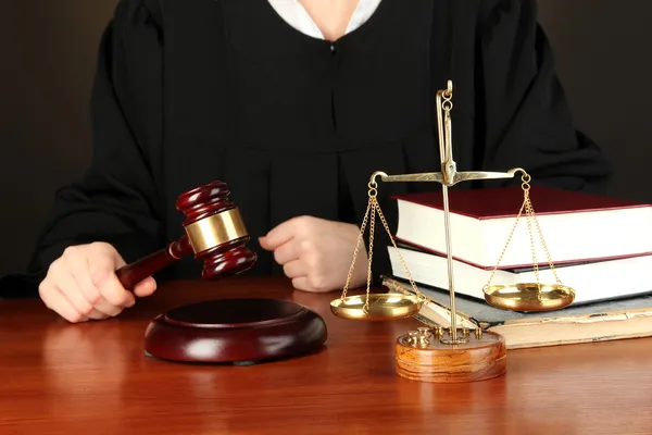 Juiz sentado à mesa durante audiências judiciais sobre fundo negro — Fotografia de Stock