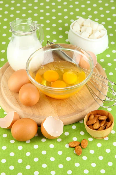 Ovo quebrado na tigela e vários ingredientes ao lado deles na toalha de mesa verde close-up — Fotografia de Stock