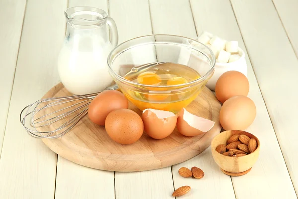 Huevo roto en tazón y varios ingredientes junto a ellos en la mesa de madera de cerca — Foto de Stock