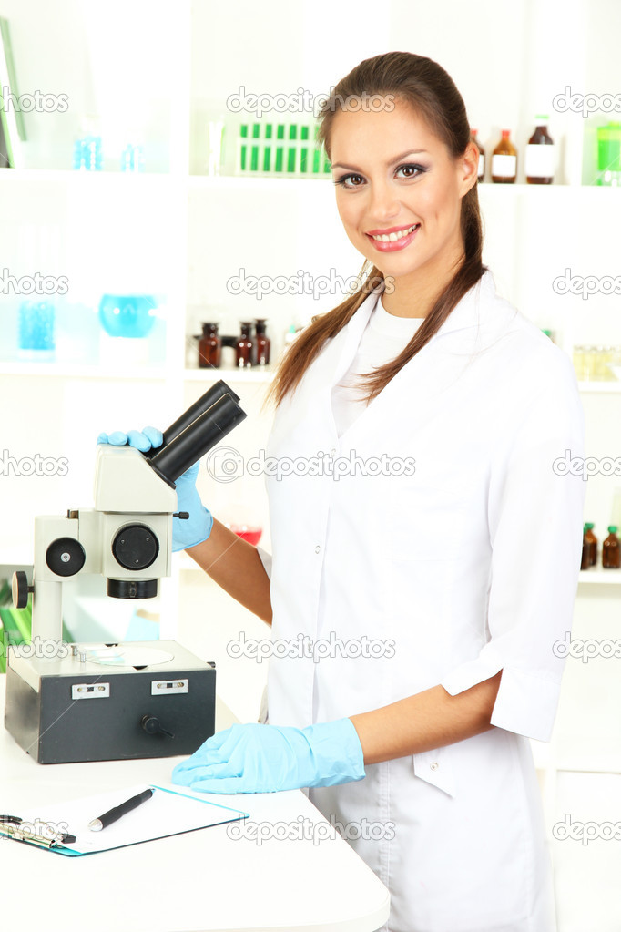 Young scientist looking into microscope in laboratory