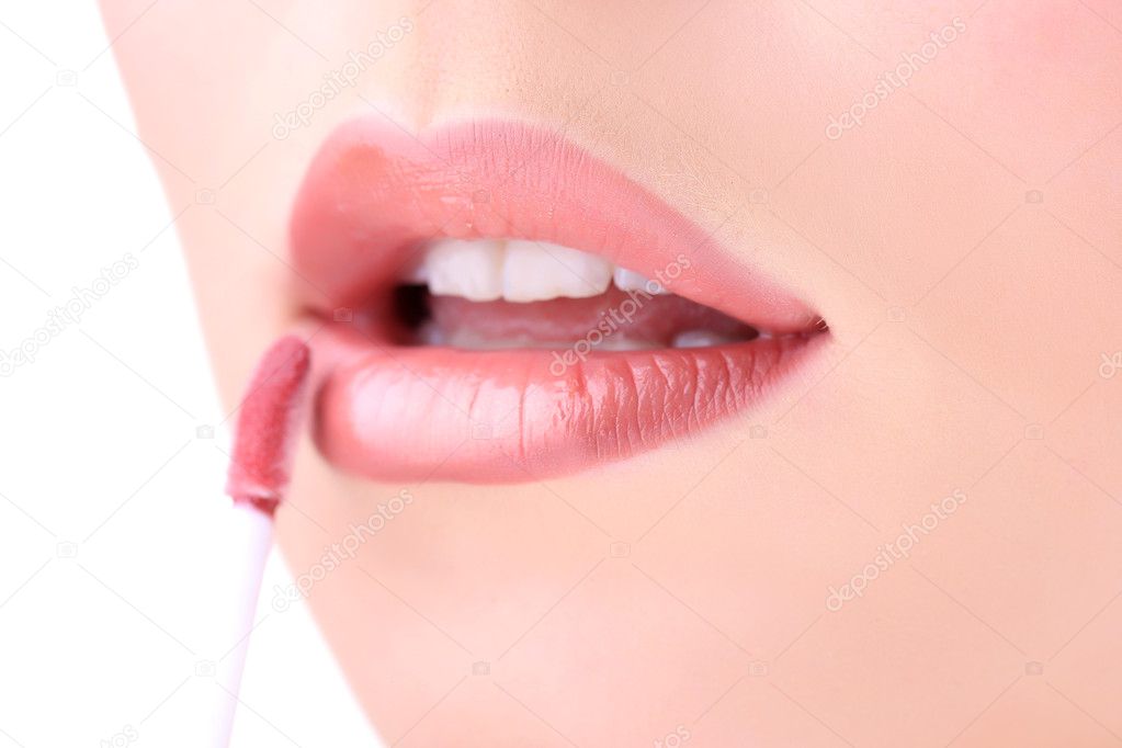 Beautiful young woman applying lip gloss, close up