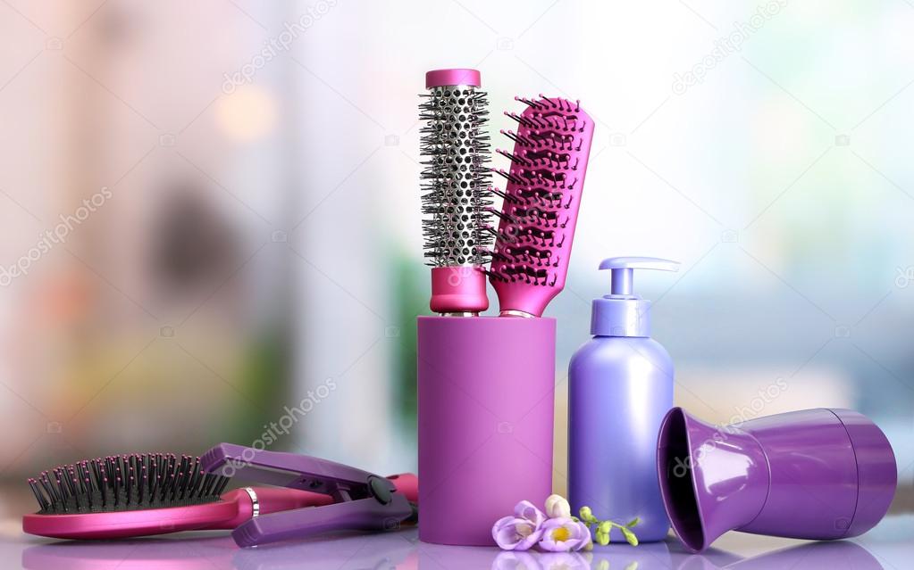 Hair brushes, hairdryer, straighteners and cosmetic bottle in beauty salon