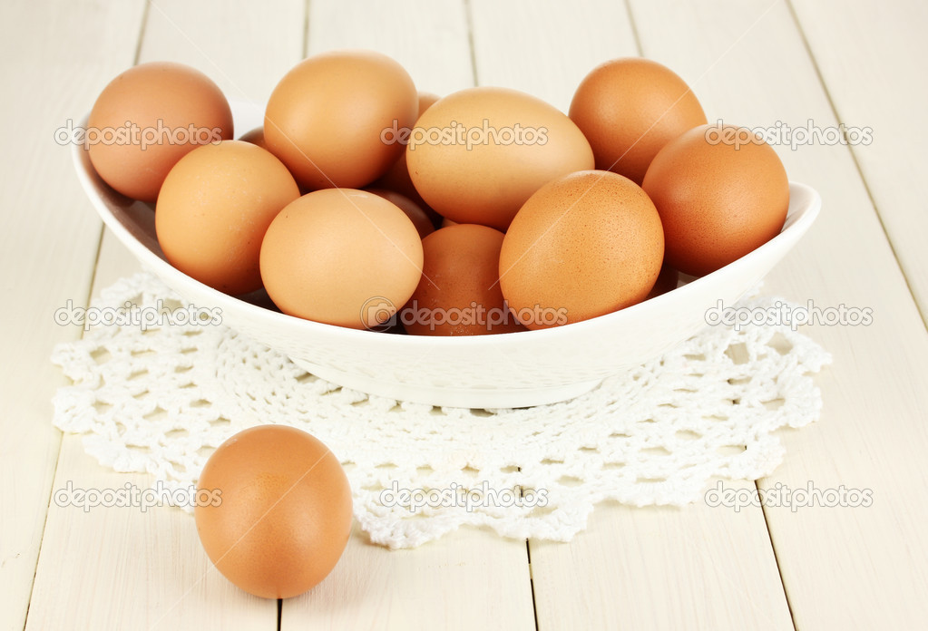 Eggs in white bowl on wooden table close-up