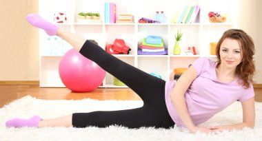 Genç bir kadın evde spor yapıyor.