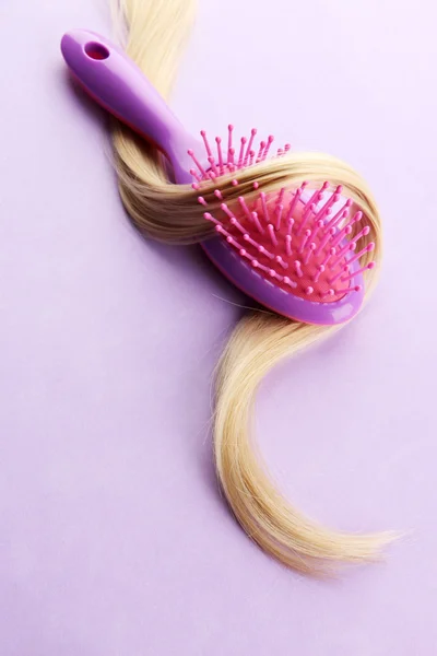 Cepillo peine con pelo, sobre fondo púrpura — Foto de Stock