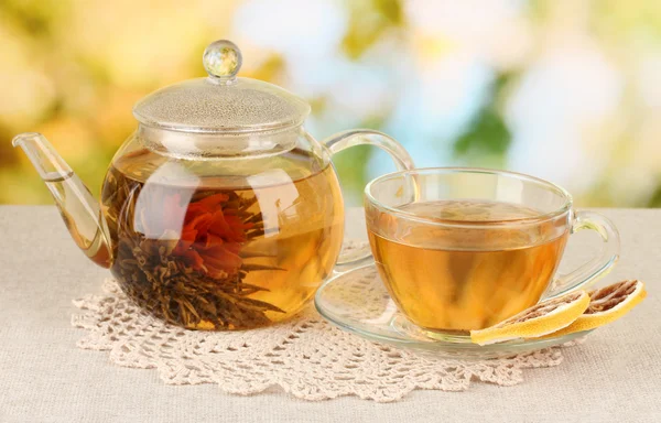 Té verde exótico con flores en tetera de vidrio sobre fondo brillante — Foto de Stock