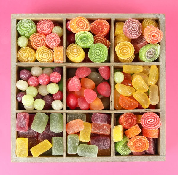 Multicolor candies in wooden box, on color background — Stock Photo, Image