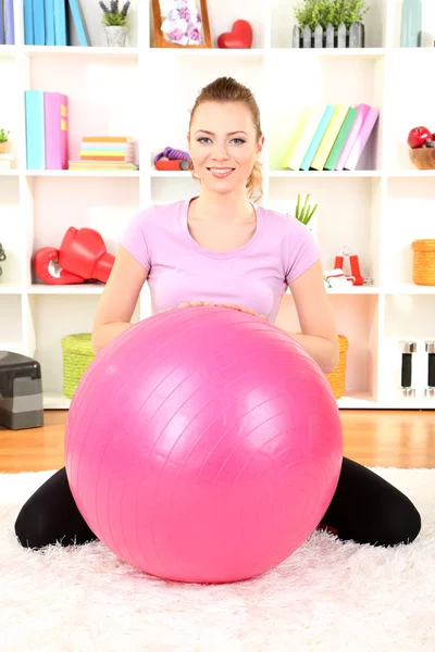 Jonge vrouw doen fitness oefeningen met gymnastiek bal thuis — Stockfoto