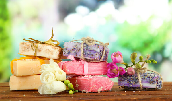 Естественное мыло ручной работы, на деревянном столе, на зеленом фоне
