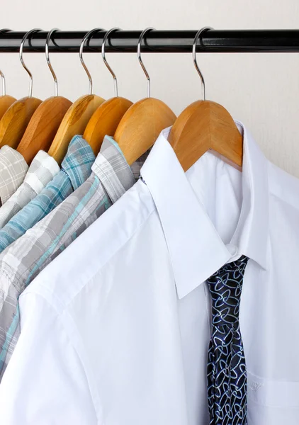 Camicie con cravatte su appendini in legno su sfondo chiaro — Foto Stock