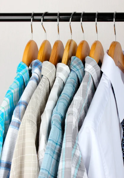 Hemden mit Krawatten auf hölzernen Kleiderbügeln auf hellem Hintergrund — Stockfoto
