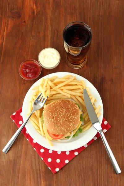 patates kızartması ve ahşap zemin üzerinde soğuk içecek ile lezzetli peynirli burger