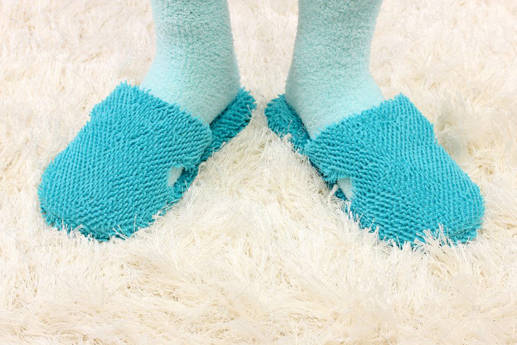 Female legs in color slippers, on carpet background