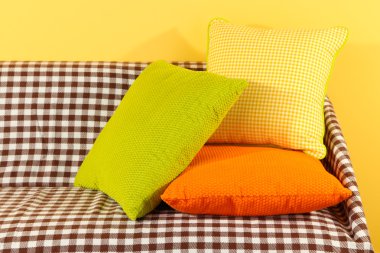 kanepede sarı arka plan üzerinde renkli yastıklar