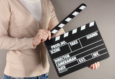 Film üretim clapper panosundaki gri arka plan üzerinde eller