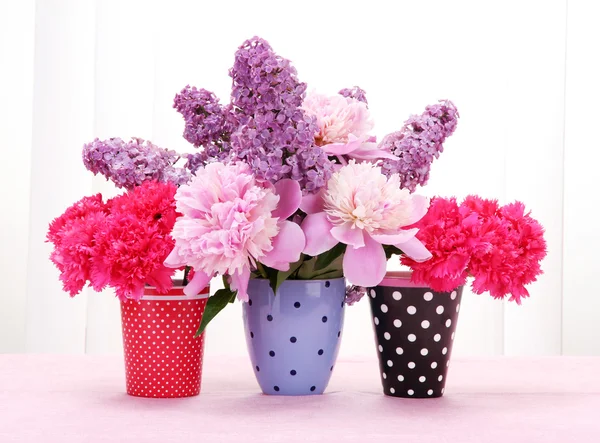 Spring flowers in cups on table on white wooden background — Stock Photo, Image
