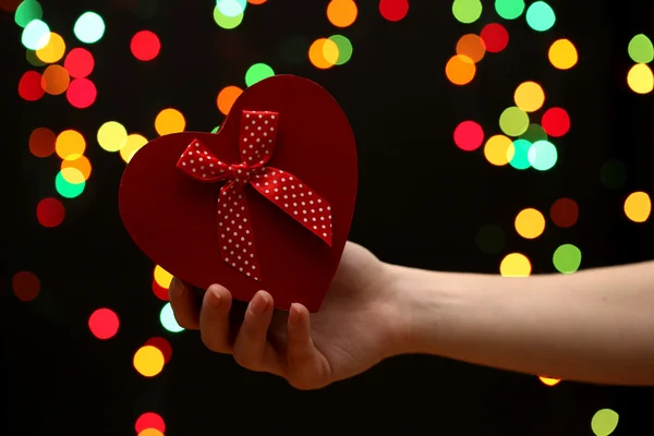 Woman hand with gift box, on garland background — Stock Photo, Image