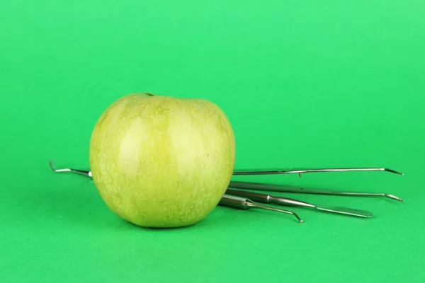 Green apple and dental tools on color background — Stock Photo, Image