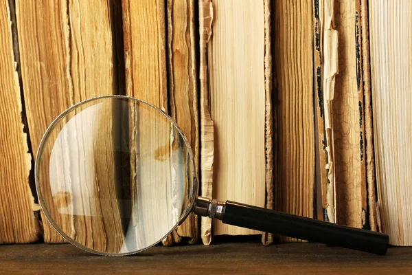 Magnifying glass and books on table — Stock Photo, Image