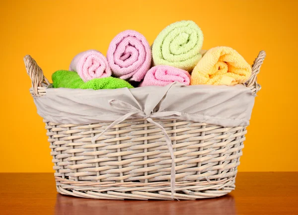 Colorful towels in basket on color background — Stock Photo, Image