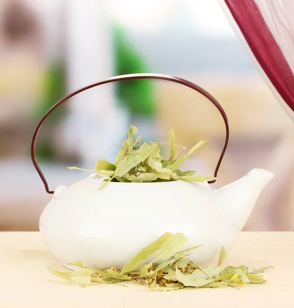 Dried herbs in teapot on wooden table, on bright background. Conceptual photo of herbal tea. — Stock Photo, Image