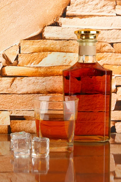 Flasche und Glas Whiskey und Eis auf Backsteinmauer Hintergrund — Stockfoto
