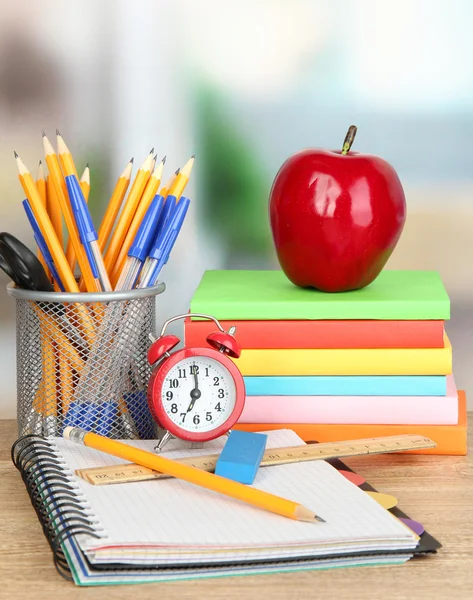 Schulbedarf mit Apfel und Uhr auf Holztisch — Stockfoto