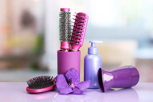 Hair brushes, hairdryer and cosmetic bottle in beauty salon — Stock Photo, Image