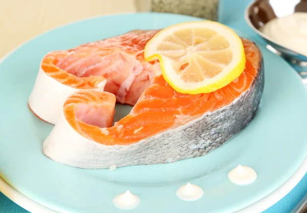 Stück roter Fisch auf Teller mit Gewürzen und Soße auf Holztisch in Großaufnahme — Stockfoto