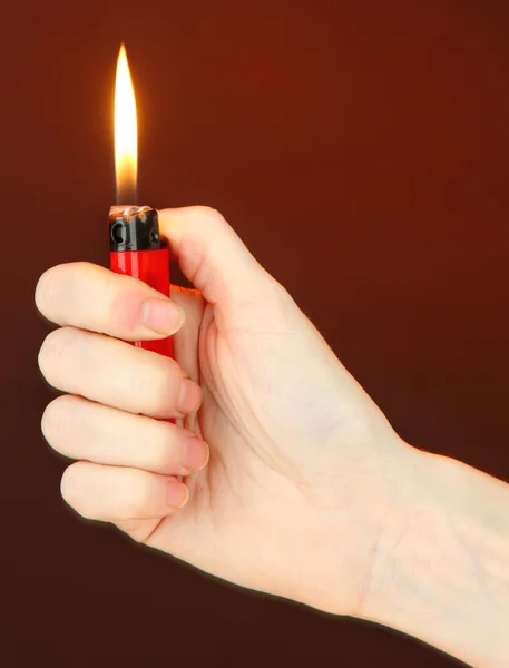 Ardiente encendedor en mano femenina, sobre fondo marrón oscuro — Foto de Stock