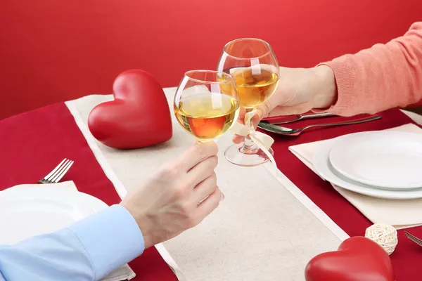 Mãos de casal romântico brindar seus copos de vinho sobre uma mesa de restaurante — Fotografia de Stock