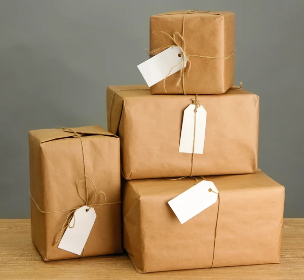 Caixas de pacotes com papel kraft, em mesa de madeira sobre fundo cinza — Fotografia de Stock