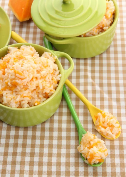 Taste rice porridge with pumpkin in saucepans on tablecloth background — Stock Photo, Image