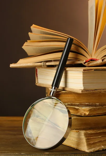 Magnifying glass and books on table — Stock Photo, Image