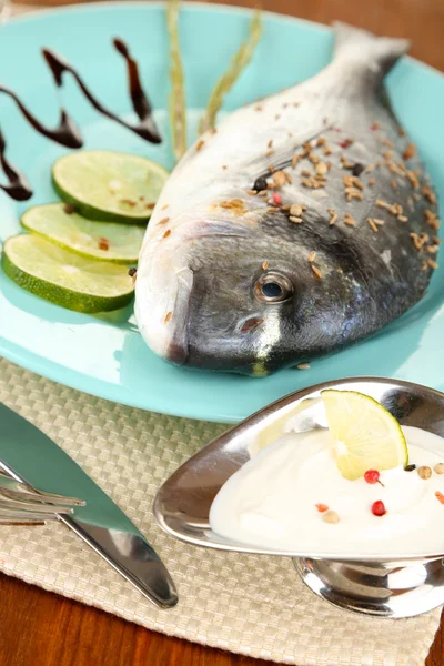Fish dorado with lemon on plate on wooden table close-up — Stock Photo, Image