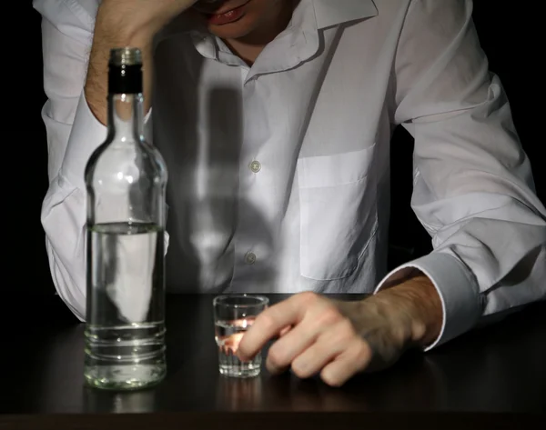 Hombre con botella de alcohol, sobre fondo negro — Foto de Stock