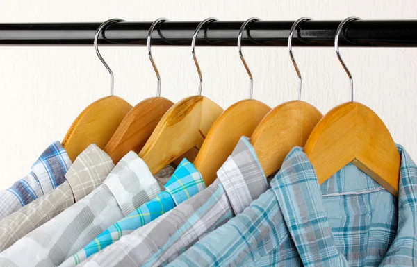 Shirts with ties on wooden hangers on light background — Stock Photo, Image