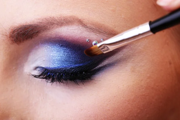Hermoso ojo femenino con maquillaje y cepillo azul brillante — Foto de Stock