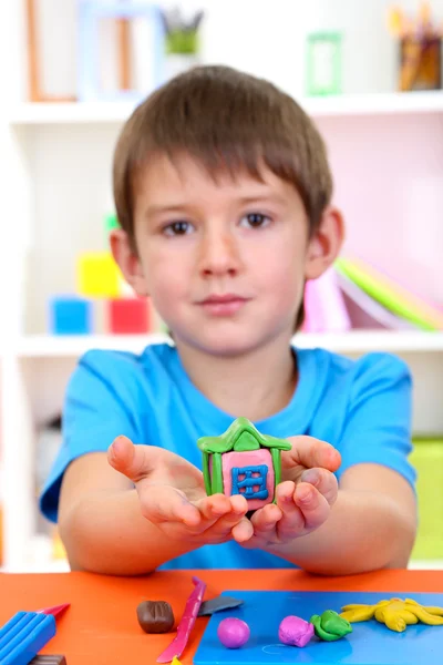 Cute little boy holding hand-made plasticine hourse over desk — Stock Photo, Image